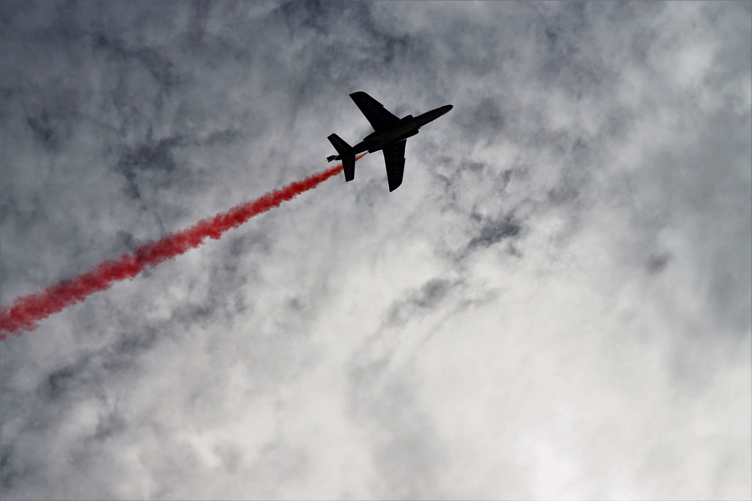 aereo nel cielo che fa una scia di fumo rosso
