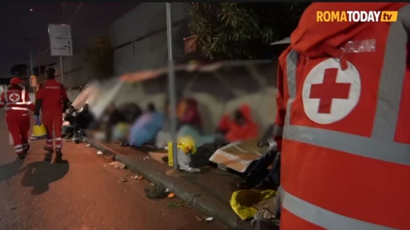 persone per terra di notte davanti alla questura di Roma assistiti dalla Croce Rossa
